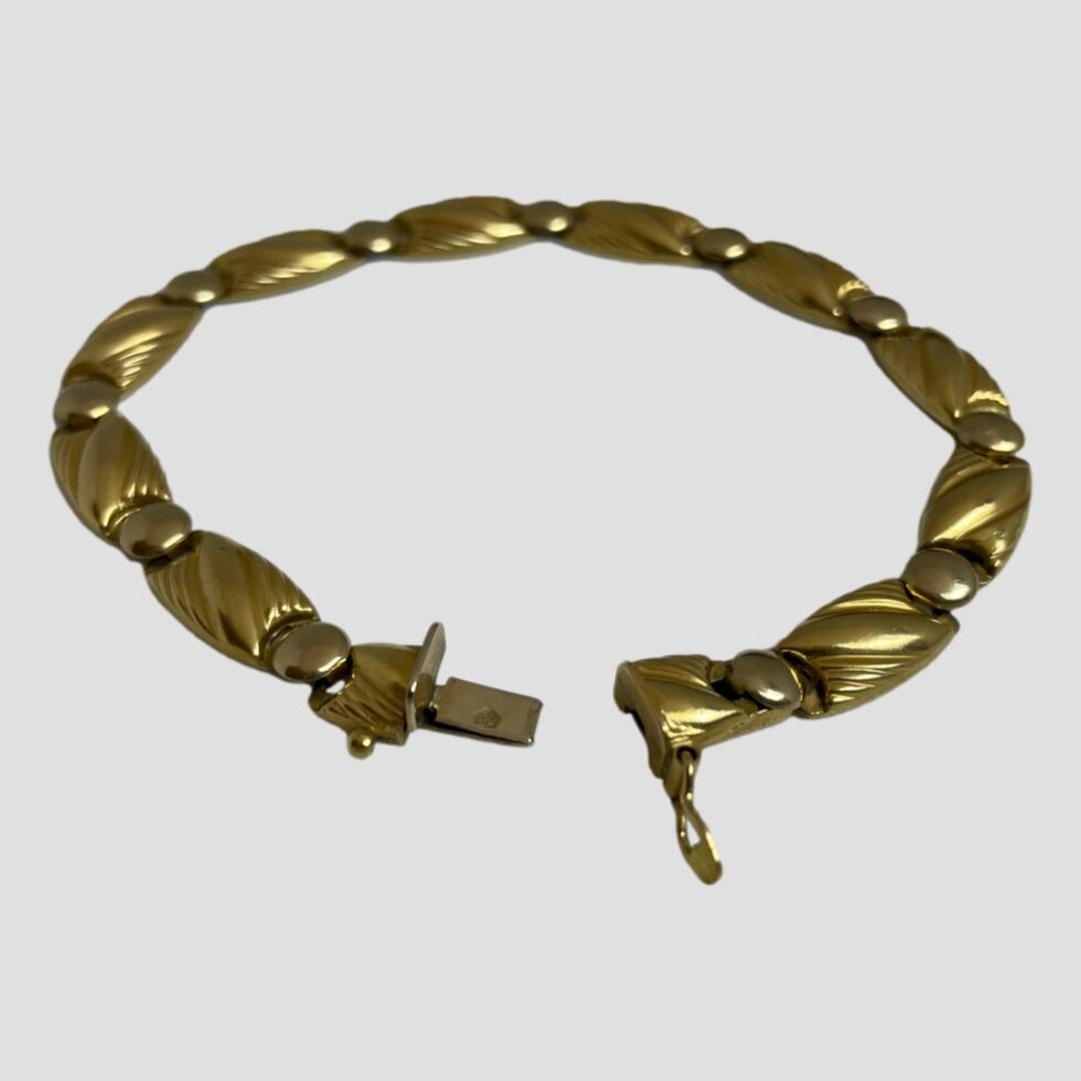 Photo of bracelet displayed on a flat surface with the clasp area in the centre foreground. The clasp is shown undone with the bracelet ends slightly apart.