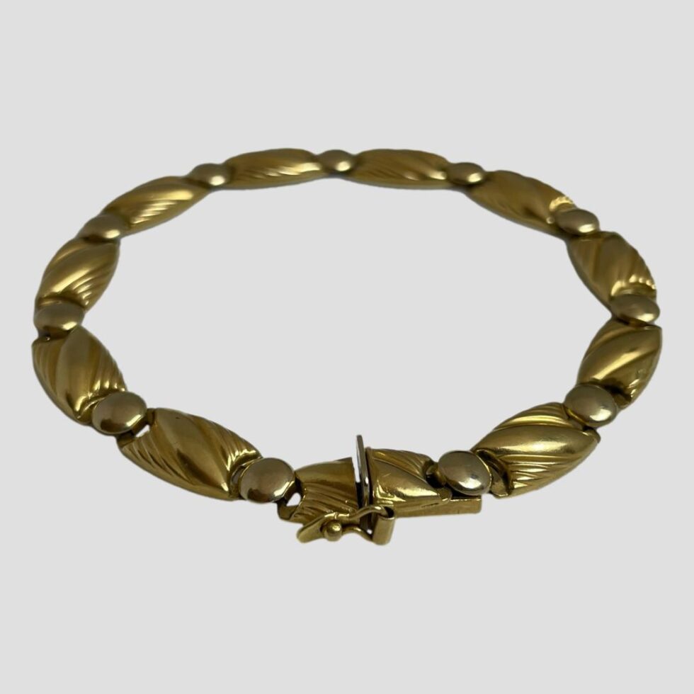 Photo of 18kt Egyptian gold bracelet displayed in a circle on a flat surface with the clasp area in the foreground.