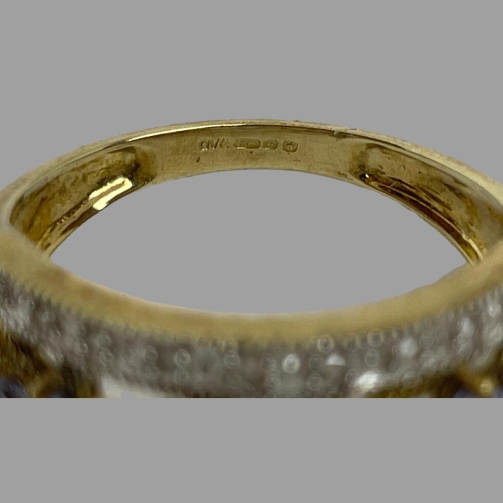 Close up photo of the hallmark on the inside band of modern gold tanzanite ring.