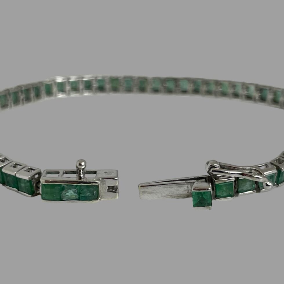 Close up photo of the clasp area shown open. The raised release button emerald setting is clearly seen here.