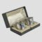 Main photo of the George V napkin rings displayed inside of their original fitted case. Some foxing and staining is visible to the silk on inside lid. The box is open to the bottom right.