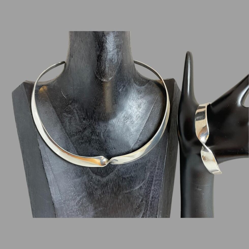 Close up of the collar necklace and cuff bracelet still displayed on their respective stands. The hand is fanned out more to the right now to show the whole collar.