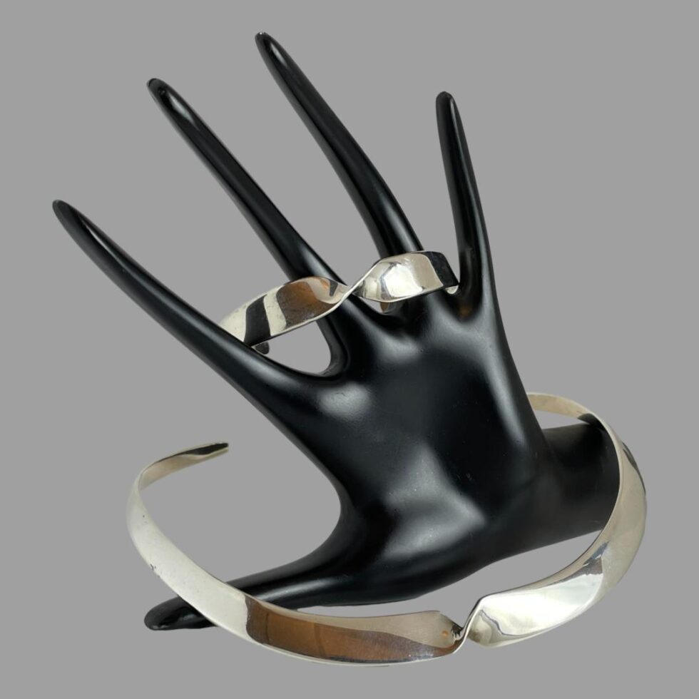 The collar necklace and cuff bracelet are now displayed together around the hand display. The cuff is around the central fingers and the collar necklace is in front.