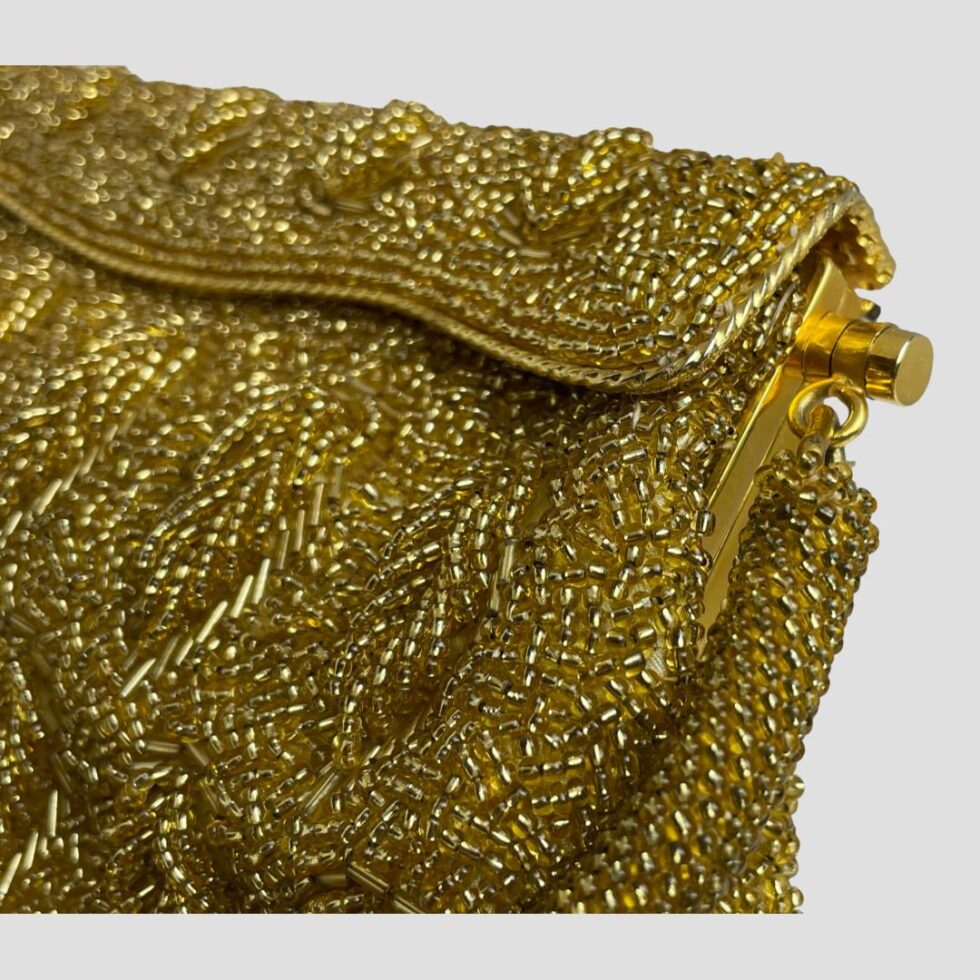 Close up photo of one end of the bag front showing bead detailing and pat of the gold metal frame.