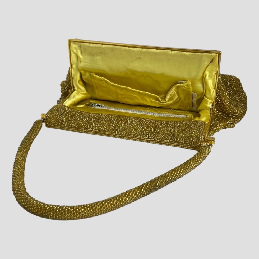 Photo of vintage gold beaded bag displayed laid flat with the bag open and handle laid in a semi circle. The lovely yellow satin lining and 2 pockets are visible (1 with zip)