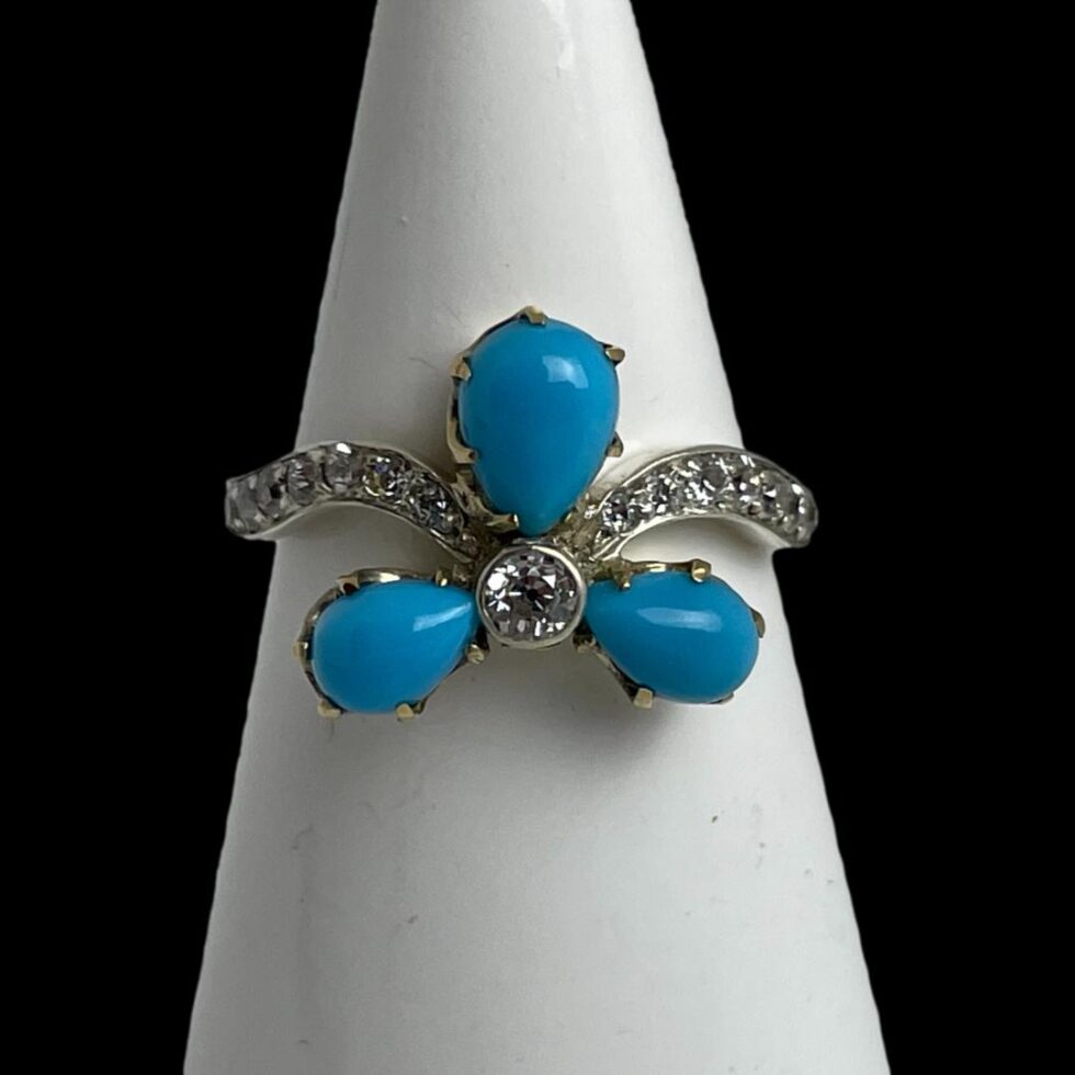 Photo of diamond and turquoise ring displayed on a white cone shaped stand and forward facing.
