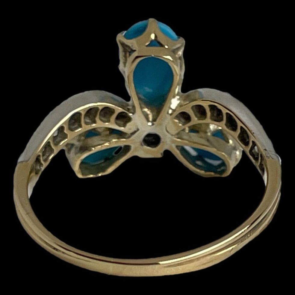 Photo of ring displayed on a flat surface seen from the back showing the setting for the stones from the back.