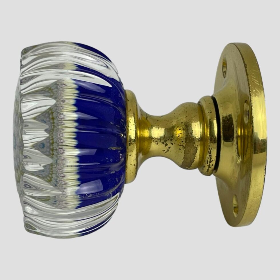 Photo of Perthshire glass door knob seen from a side view with the glass end on the left. The cobalt blue base colour is clearly seen to the right of glass knob, the millefiori start in the middle and clear glass to the left.