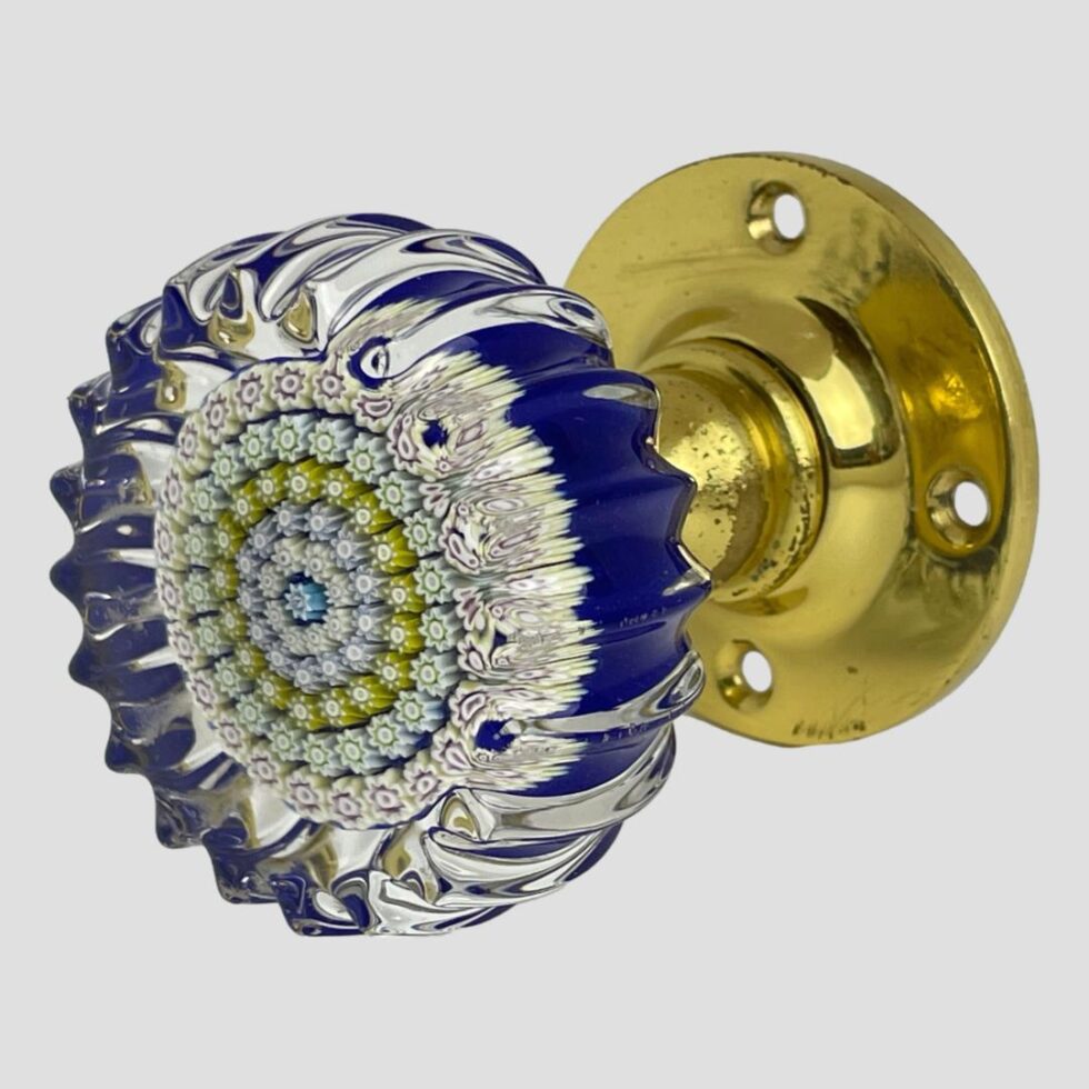 Photo of Perthshire millefiori door knob displayed with the glass end in the bottom left corner foreground and the brass door fixing to the back right.