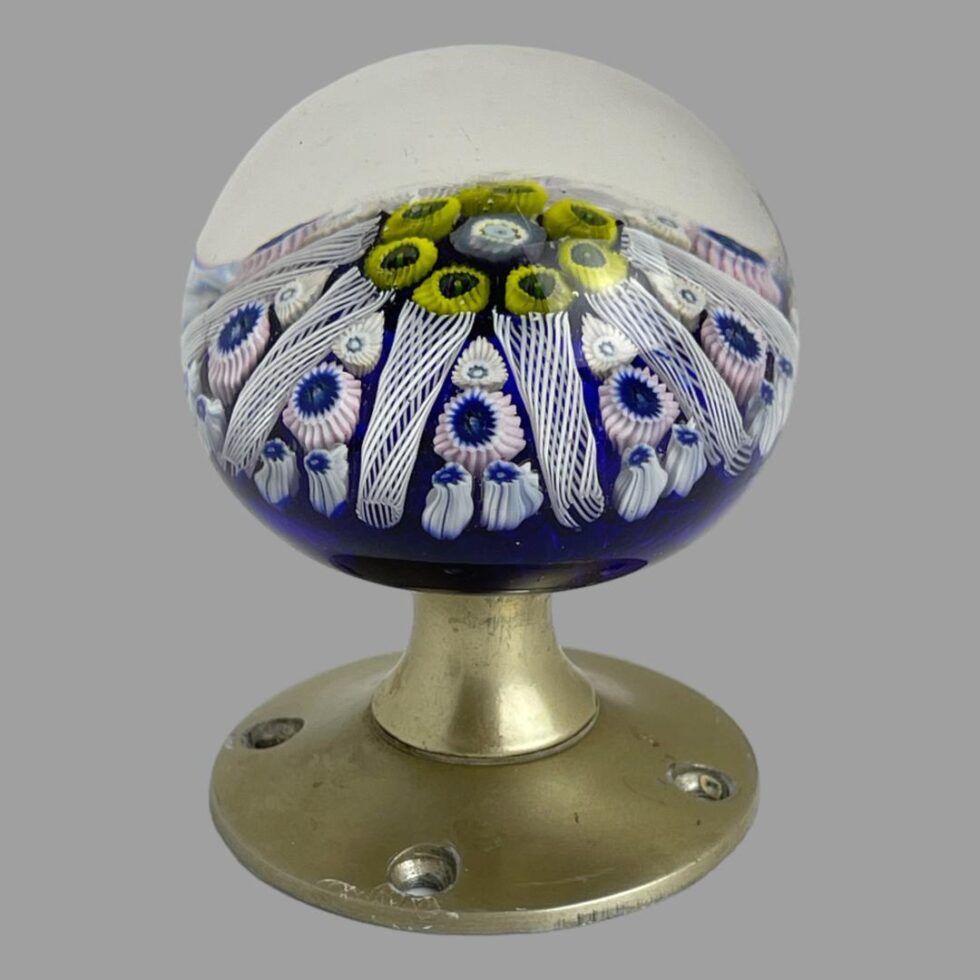 Photo of Strathearn glass door knob displayed stood upright on its brass coloured metal door fixing.