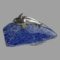 Main photo of Georg Jensen dolphins brooch displayed on top of a small rock of lapis lazuli. They are swimming side by side with one in front of the other. Bodies are arched as if in real swimming motion.