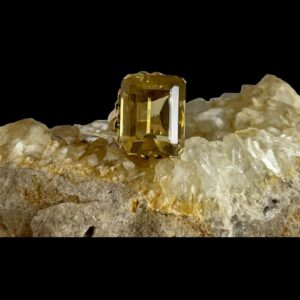 Main photo of faceted citrine gold ring displayed on a rock of natural river quartz with the large ring front forward facing. This is a substantial sized citrine stone which has been beautifully faceted and set on 14 karat gold. The ring band is very unusual with one end at top of stone and other at bottom. This unusual design ensures the stone stays in place without turning which often happens with large stone rings.