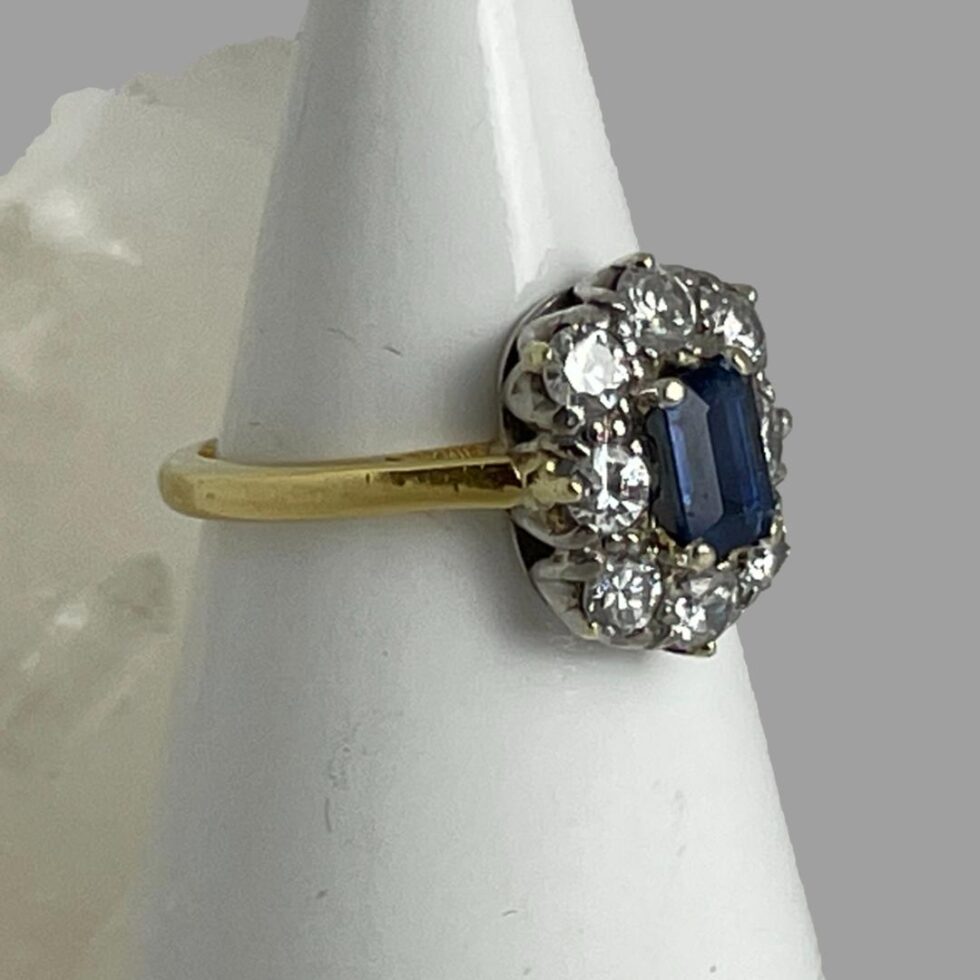 Photo of the cornflower sapphire and diamond ring still displayed on a cone shaped stand this time with the ring front facing towards the bottom right corner. The ring has no fancy shoulder as it is not required!