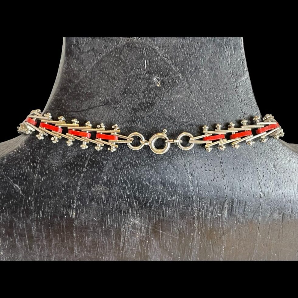 Photo of the clasp area shown still displayed on a black wooden display stand. The chrome and red enamel carries on throughout the whole piece.