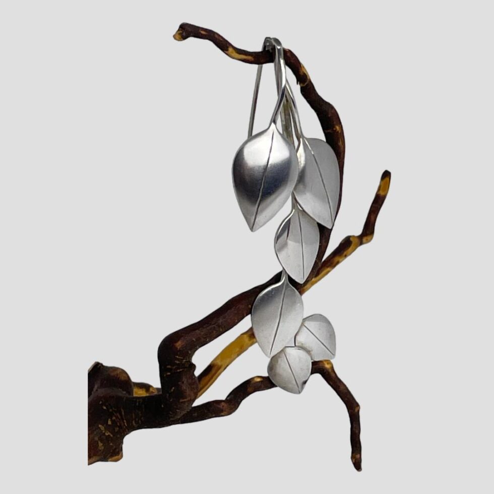 Photo of articulated silver leaf brooch still displayed hanging from the old cherry twig with the brooch front facing bottom right corner.