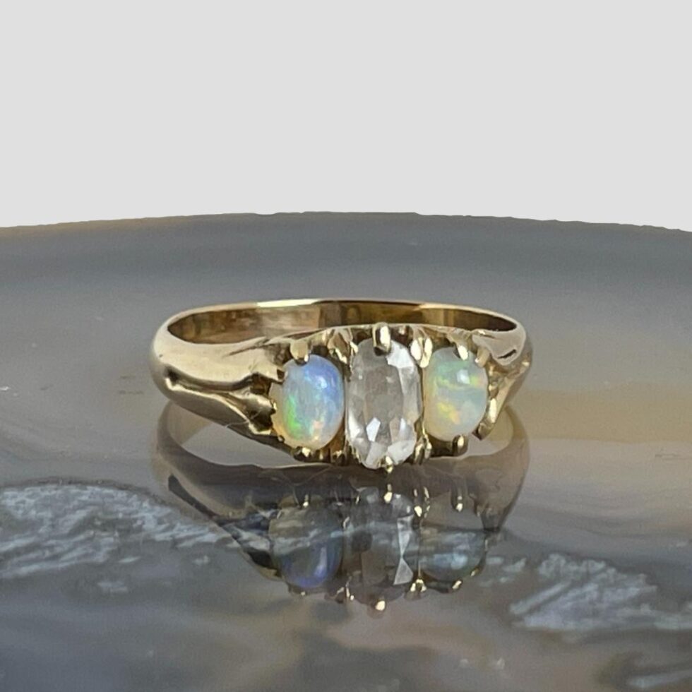 Victorian opal &diamond ring on a slice of agate with ring front forward facing. The opals are dancing with colour.