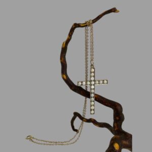Main photo of gold opal cross &chain displayed hanging from a polished twig of cherry tree. The chain has been wound round the top twig and the cross is hanging lower down. The clasp end of the chain is to the left and on the surface. At this angle the opals look almost plain white.