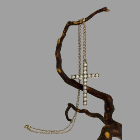 Main photo of gold opal cross &chain displayed hanging from a polished twig of cherry tree. The chain has been wound round the top twig and the cross is hanging lower down. The clasp end of the chain is to the left and on the surface. At this angle the opals look almost plain white.