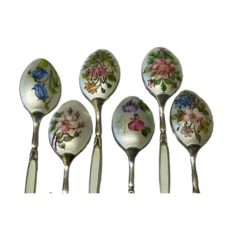 A close up photo of the back of each spoon bowl showing all of the floral decorations. The spoons are laid 3 up 3 lower but all facing same way so all the flowers are together.