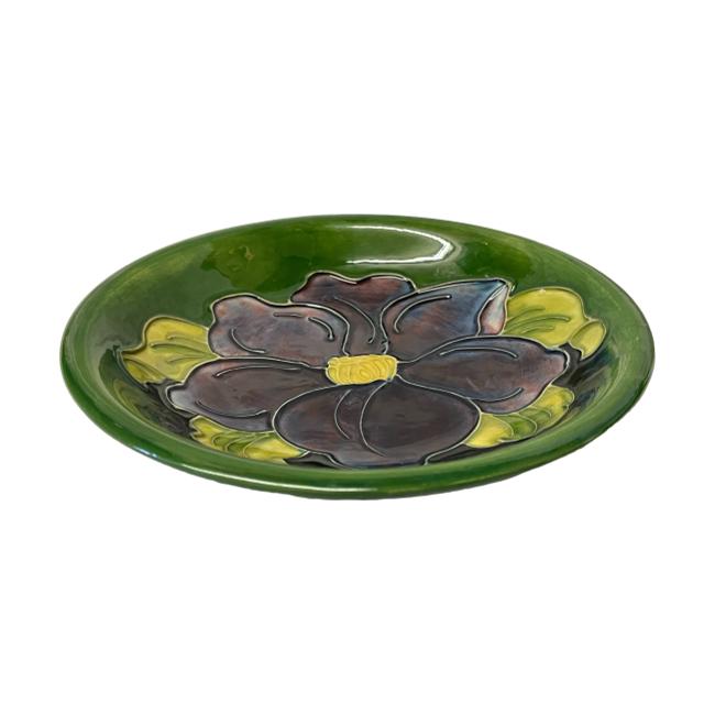 Photo of Moorcroft clematis shallow bowl displayed on a flat surface. We are looking diagonally down at the bowl from a slight height.