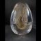 Main photo of vintage Murano egg paperweight displayed against a dark grey background. On the inside of the egg is a golden egg shape in net form so an egg shape made up of golden criss-crossed strands. The exterior of the egg is clear glass. A beautifully and expertly crafted piece.