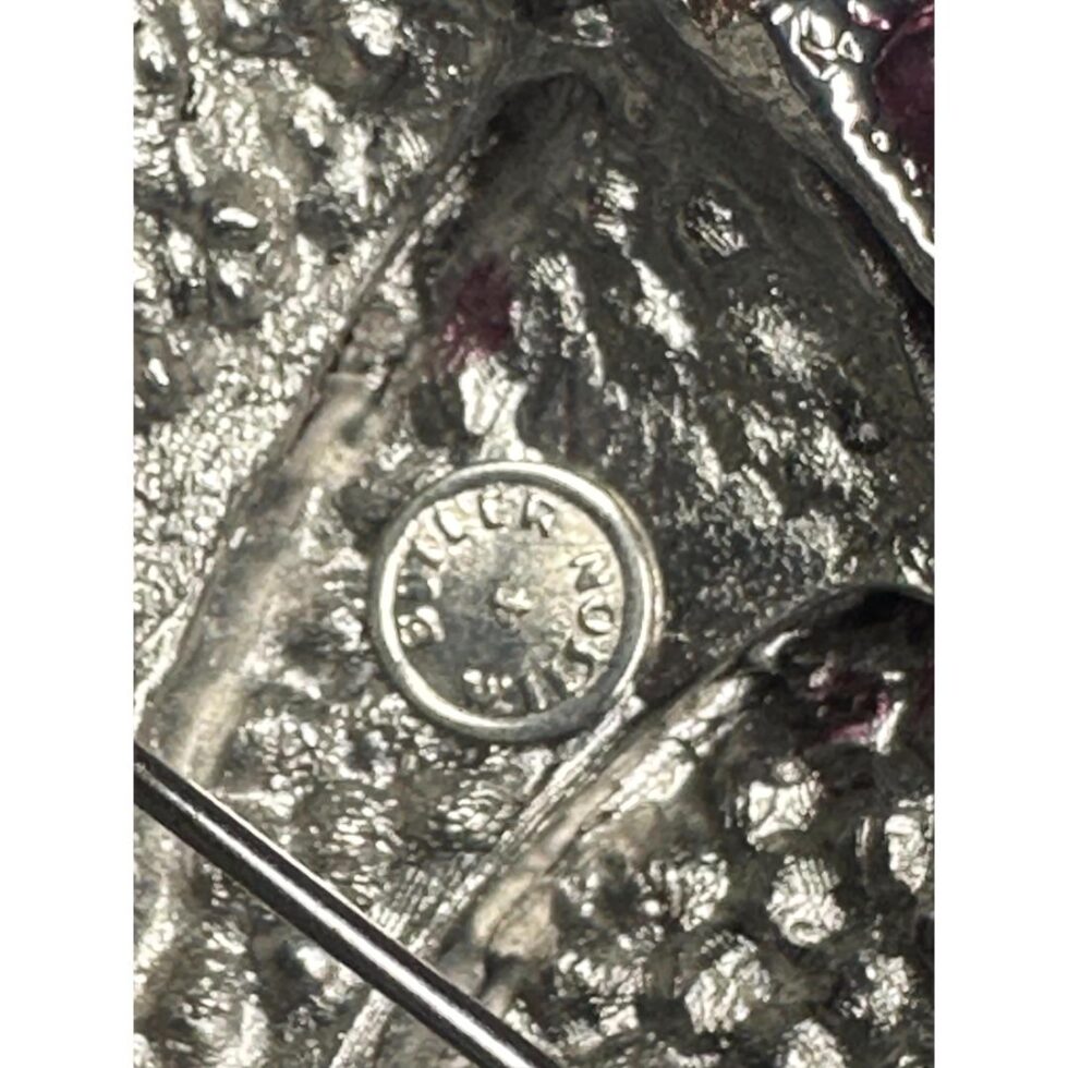 Close up photo of the Butler & Wilson button mark on the rose head behing the pin.