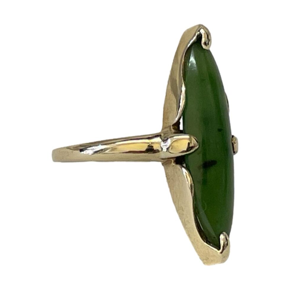 Photo of jade gold ring seen from a slight side angle with the slim jade stone facing towards the bottom right corner.