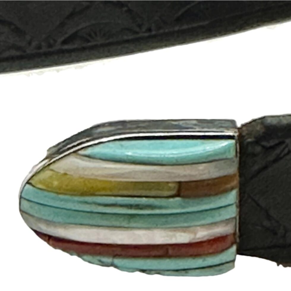 Close up photo of the belt tip which is inlaid with turquoise, coral,