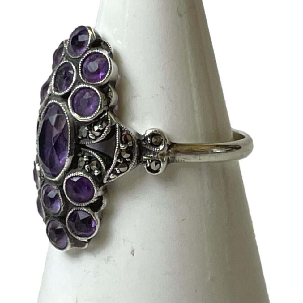 Photo of silver and amethyst ring displayed on a cone shaped stand with ring front facing left.