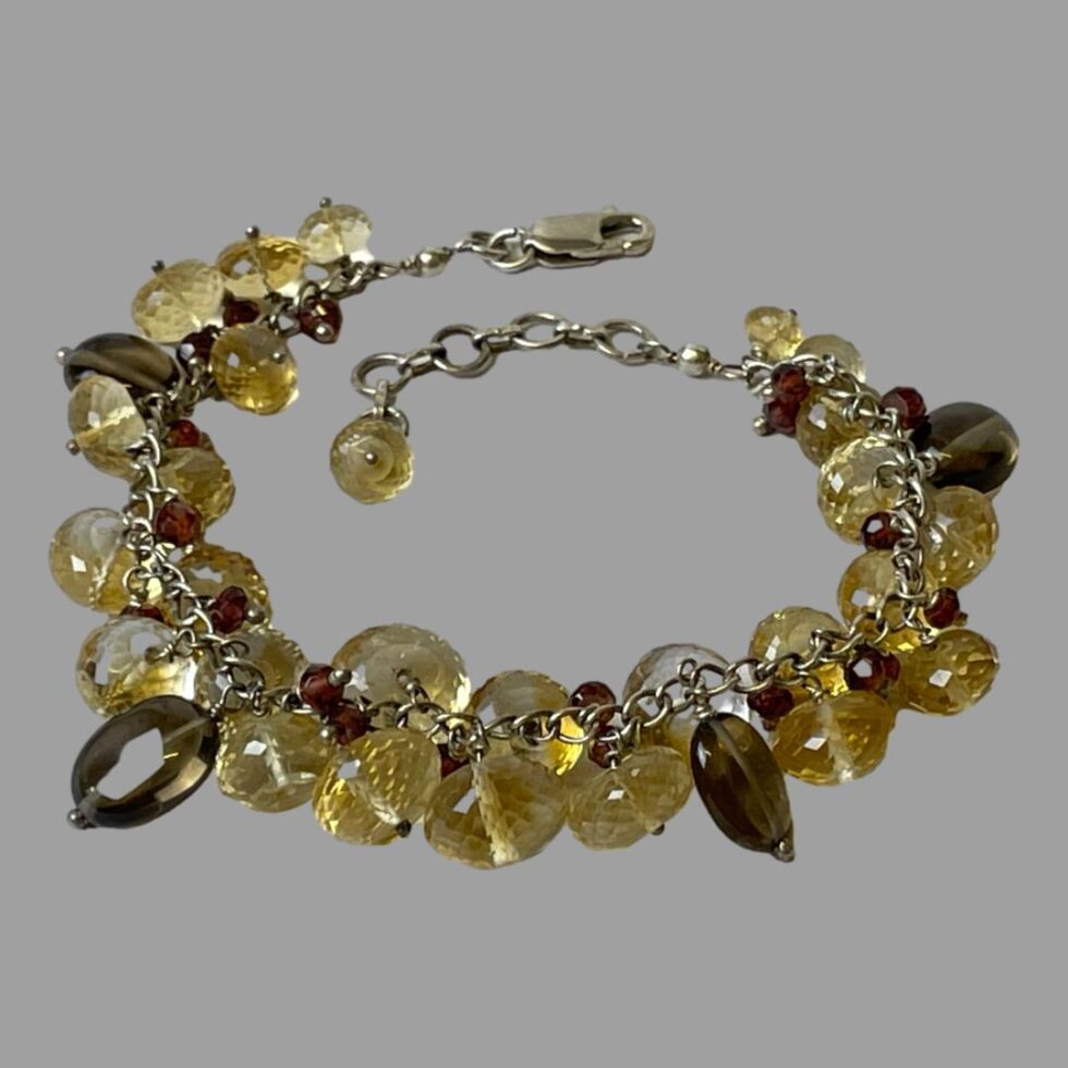 Photo of silver quartz crystal bracelet displayed in a circle on a flat surface this time with the clasp shown open. There is a single faceted champagne quartz bead at the end of the extended chain.