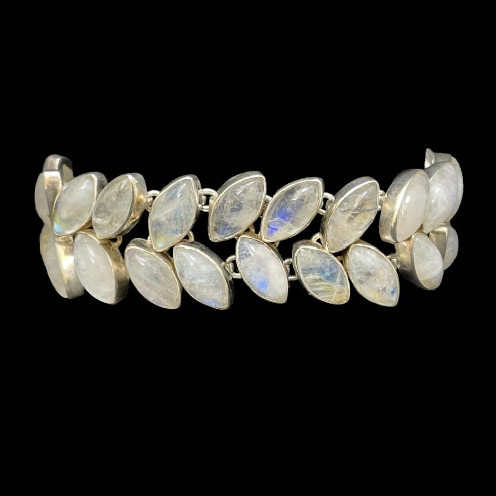 Photo of bracelet displayed on a black bracelet stand against a black background. Most of the stones appear white here and only a few with hints of blue. The stand is laid vertically so the 2 rows of stones are shown upright.