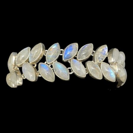 Main photo of vintage rainbow moonstone bracelet displayed around a black display cushion against a black background. The stones to the centre are the most vibrant blue with the others white with hints of blue. The top row of stones is leaning to the right and lower row is leaning to the left.