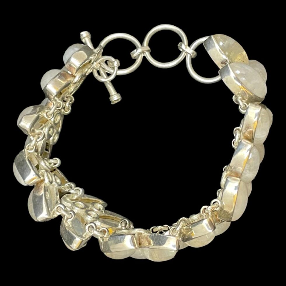 Photo looking straight down at the bracelet which is still displayed upright with clasp closed. The links holding the stone settings together can be seen. It is a vast network of rings and links. A true quality piece. The stones are showing as a white yellow colour here.