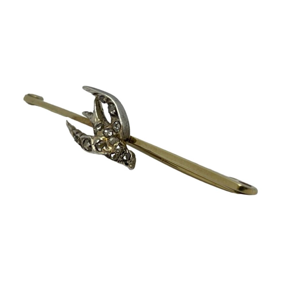 Photo of Edwardian diamond swallow brooch displayed diagonally across the page with the swallow at centre facing towards the bottom left corner.