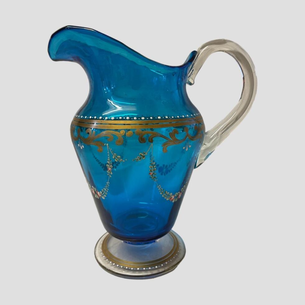 Photo of antique Bohemian glass jug displayed with the jug facing left and seen from an eye level. Here, the height of the spout is visible (highest point of jug)