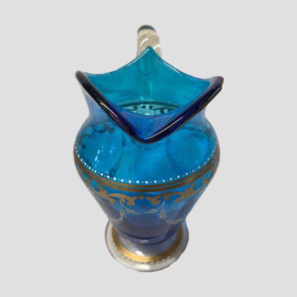 Photo of antique Bohemian glass jug displayed with the spout in the foreground and the shot taken from a slightly raised angle looking down just inside the jug.