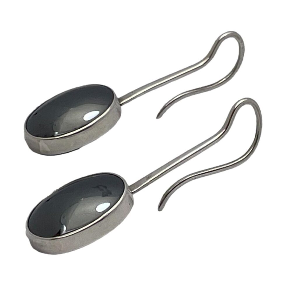 Photo of both earrings laid side by side on a flat surface. The earrings are displayed diagonally across the page with the hematite ends in bottom left corner. The clever design of these earrings have the silver hook as part of the post from which the stones hang. The hooks being extra long therefore extra secure!