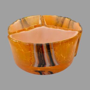 Main photo of Milan Nosek nest of bowls art glass showing all three pieces laid out a circle with each third creating the whole., The overall colour is a vibrant orange with brown and white vertical strips around the centre area of bowl exterior. Each segment of bowl has different strips.