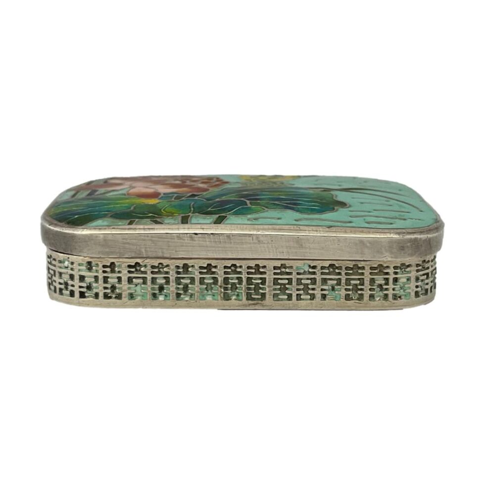 Photo of Korean silver &enamel box seen from an eye level with the wider side in the foreground. The wear of the enamel to the side is visible.