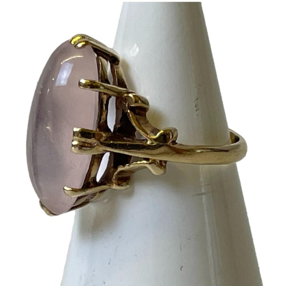 Photo of gold rose quartz ring still displayed on a cone shaped stand this time with the ring front facing straight left. The gold framework for this ring is quite extensive - something more often suited to precious stones. This rose quartz may hold magical powers!