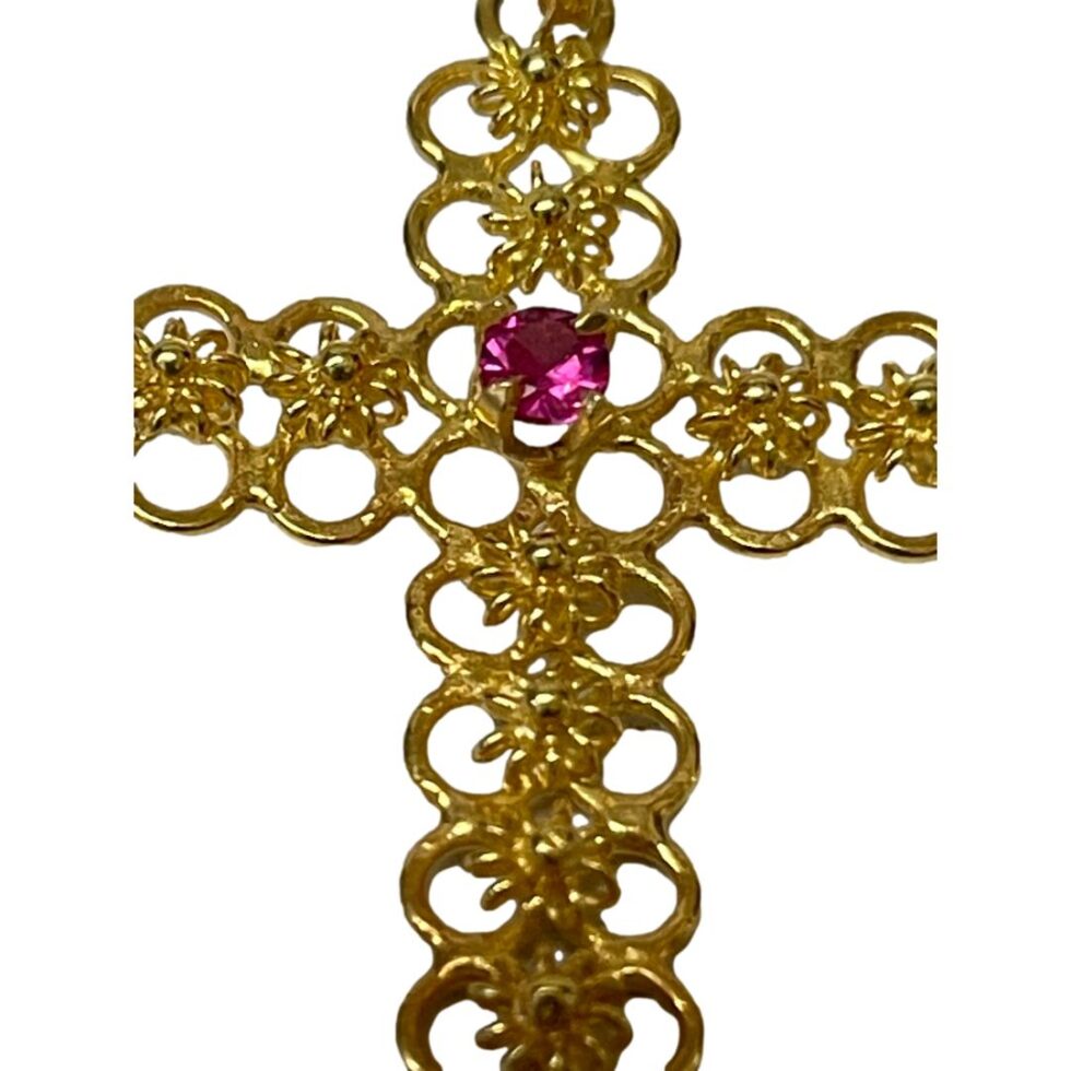 A close up photo of the ruby and the floral detail on the 18kt gold cross.