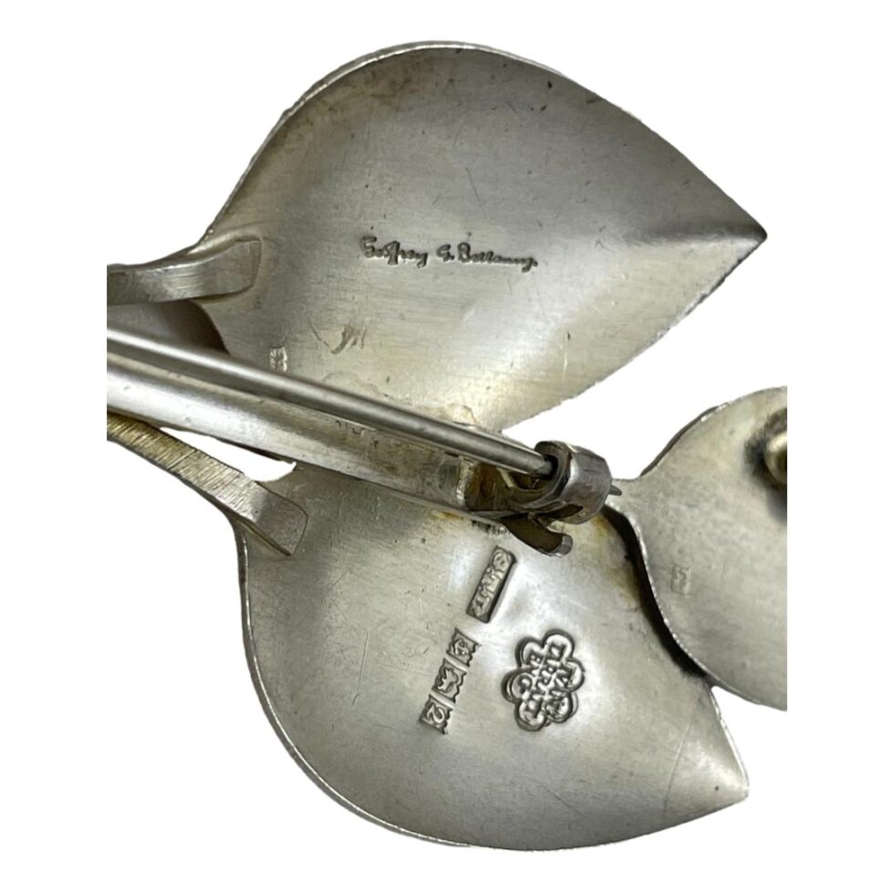 Close up photo of the 2 hallmarks. On the back of top leaf, the signature of Geoffrey G Bellamy and on leaf below, stamp of Ivan Tarratt and full hallmark.