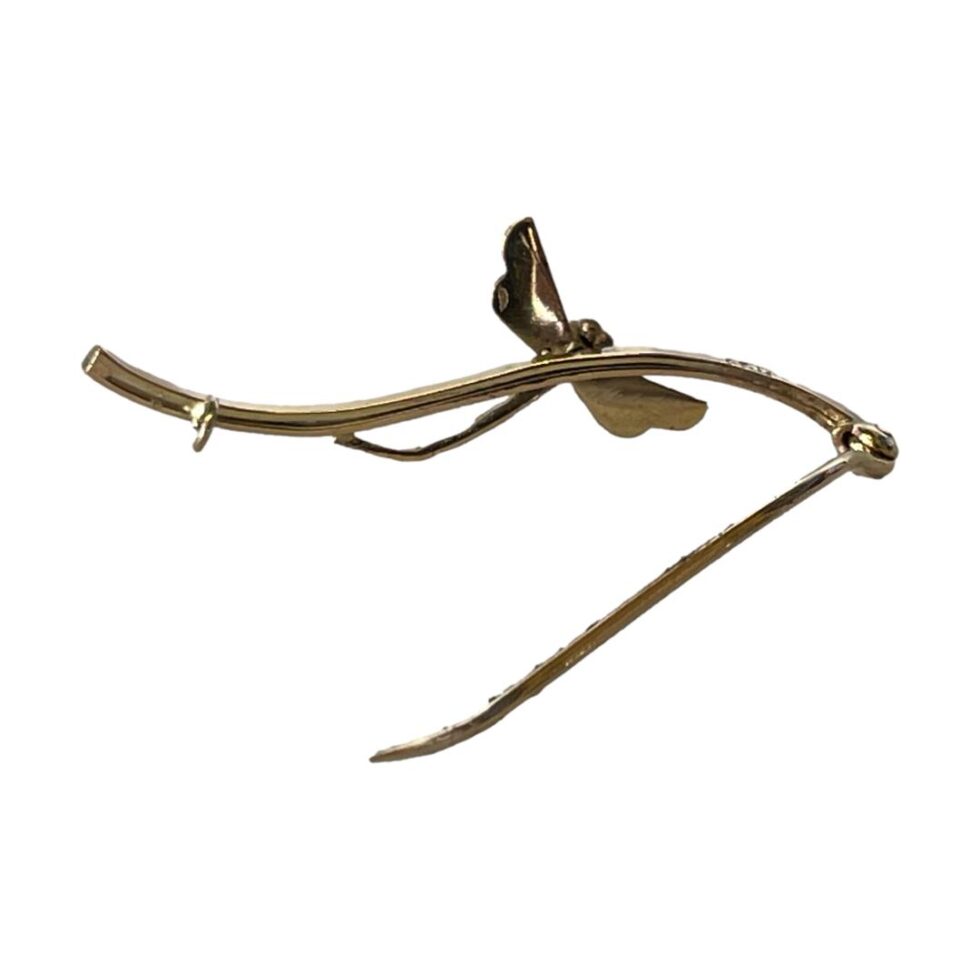 Photo of gold garnet dragonfly brooch displayed from the back. The brooch pin is shown open and propping up the brooch.