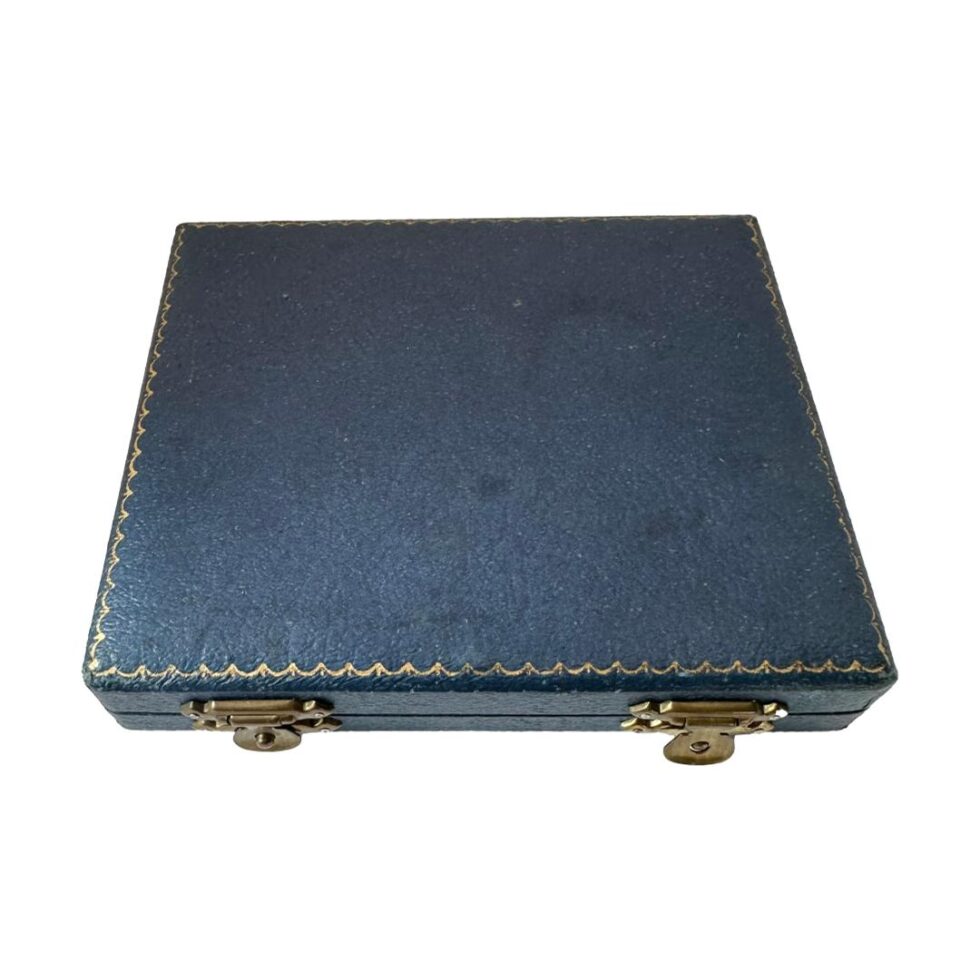 Photo looking straight down at the top of the closed case housing the spoons. It is in good condition with only minor staining.