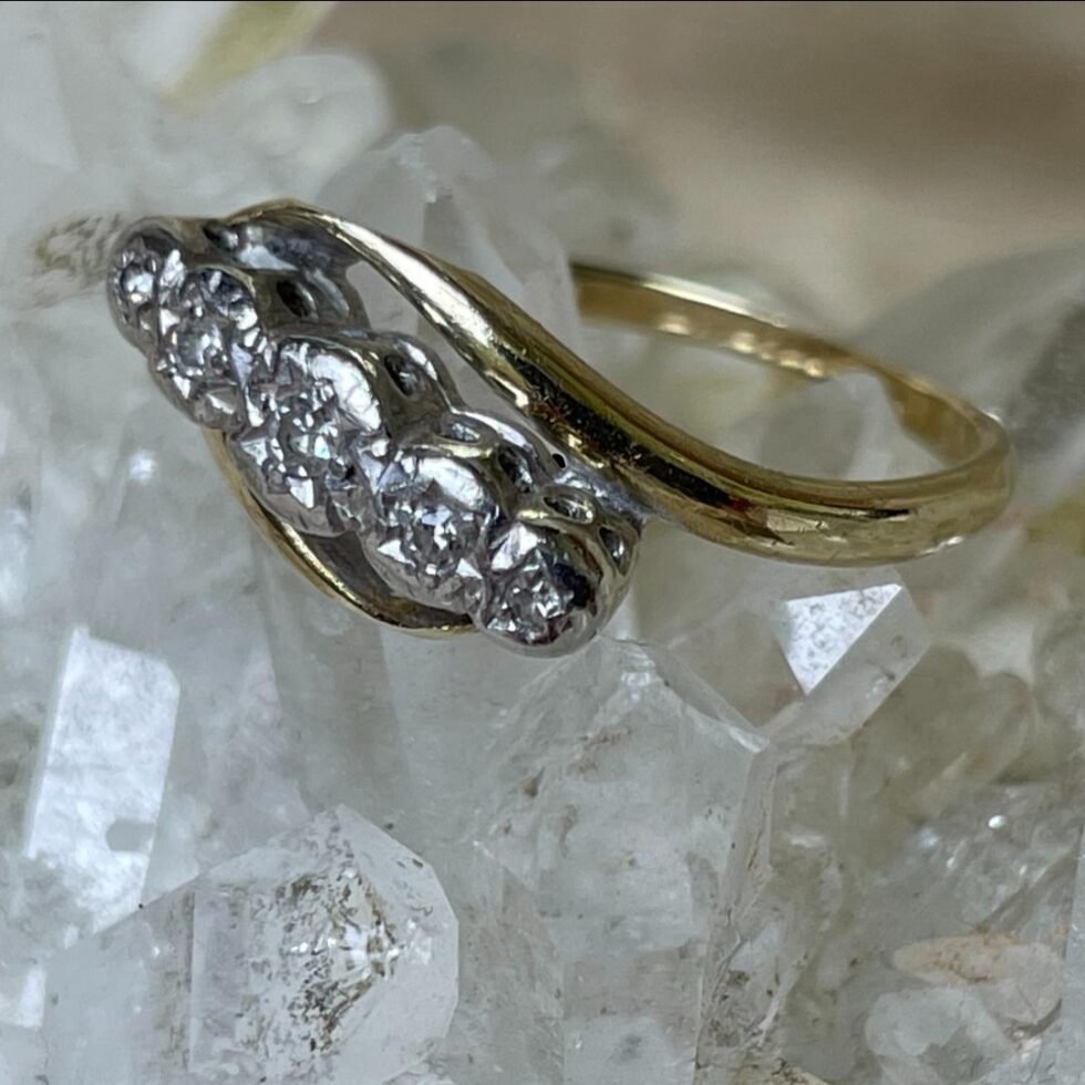 Photo of gold platinum diamond ring still displayed on top of a rock of natural quartz crystal with the ring front facing towards bottom left corner. The photo is taken from a little height looking down at the platinum gallery.