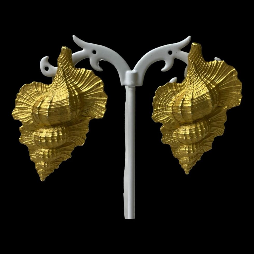 Main photo of designer shell clip-on earrings displayed on a white display stand and set against a black backdrop. The conch shell earrings are in a lovely gilt colour and very realistically crafted. Would look wonderful with a black and golden gown. Very Hollywood!
