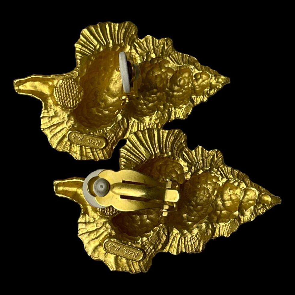 Photo of both earrings displayed on a flat surface and shown face down. The earring at top has lip open and bottom one is closed.