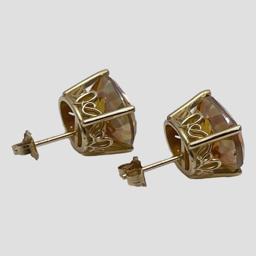 Photo of both studs laid side by side and displayed from side angle showing the pretty gold back setting of the stones, The earring fronts are faced to the right.