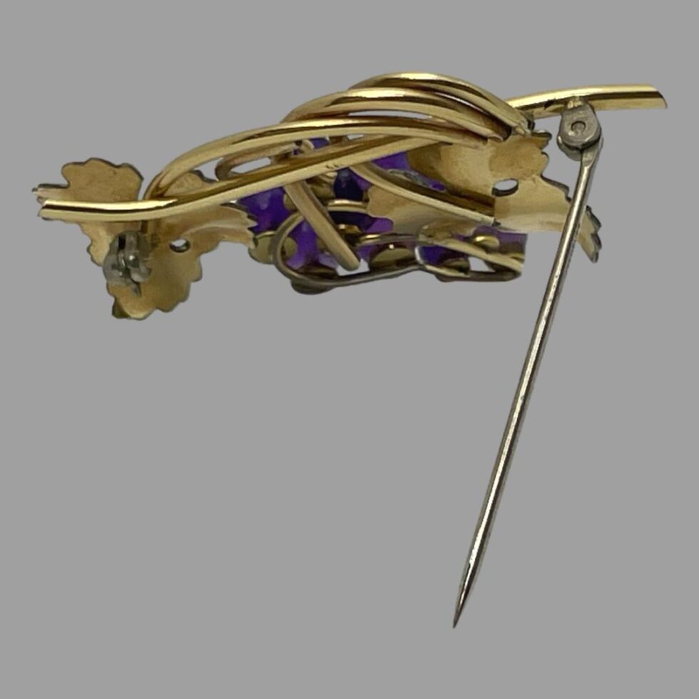 Photo of back of brooch which is propped up by its own pin.