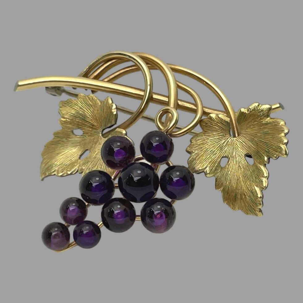 Photo of brooch displayed propped up by its own pin and seen from the front.